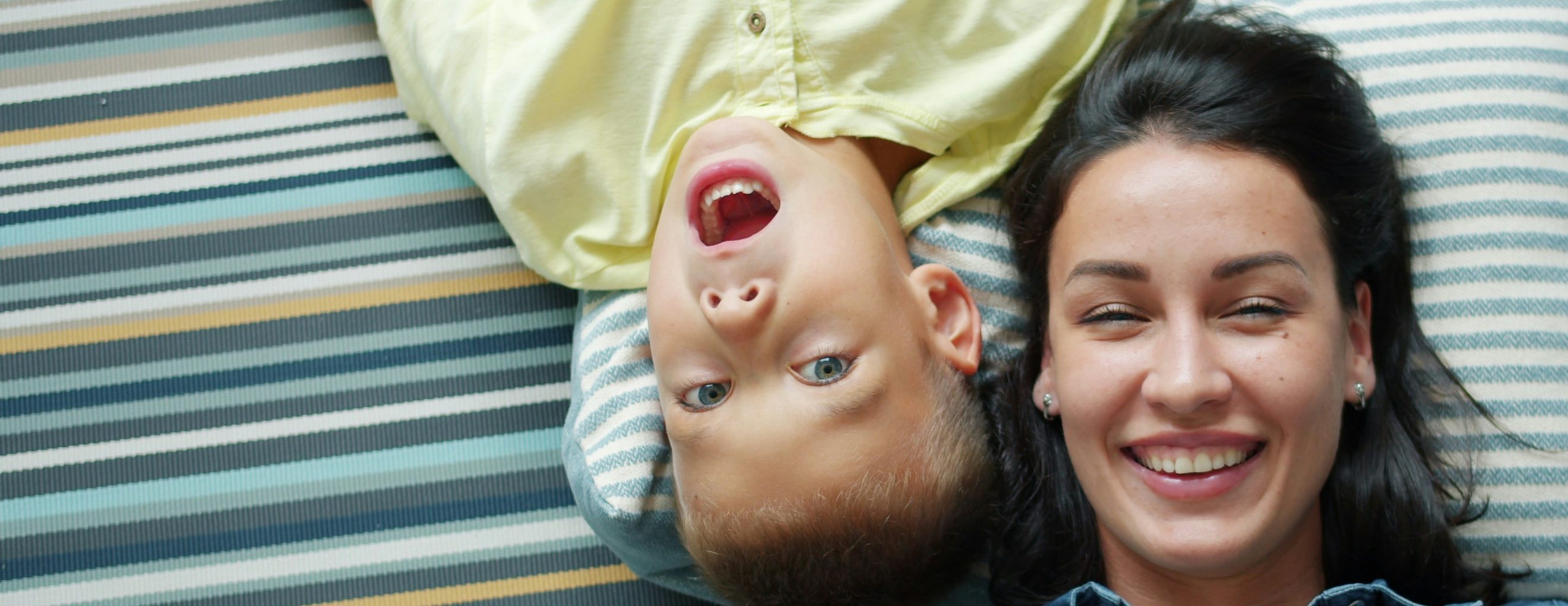 Mother and young son laughing together on a couch