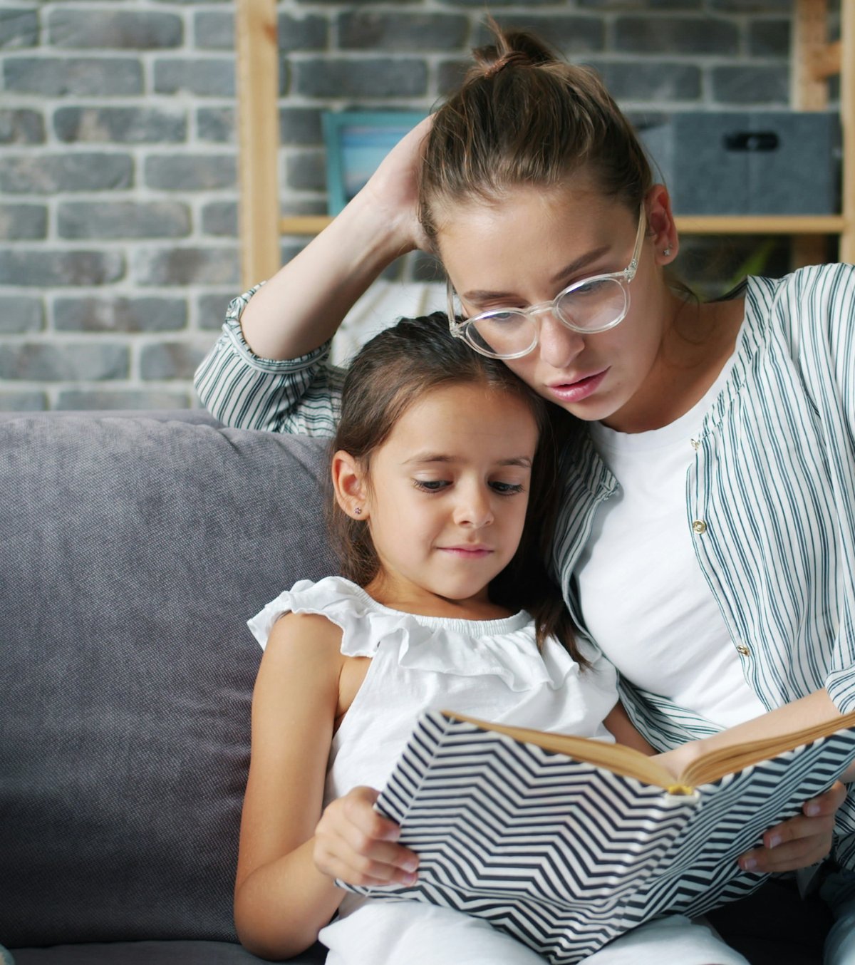 Mother and daughter reading a book together on the couch